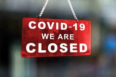 Red sign on window informing that the business is closed due to covid-19