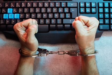 man in handcuffs in front of a keyboard