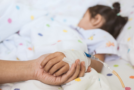 parent holding daughter's hand in hospital